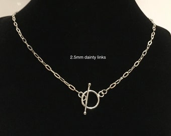 Könnte beinhalten: Eine silberne Halskette mit einem Toggle-Verschluss. Die Kette besteht aus zarten Gliedern von 2,5 mm.