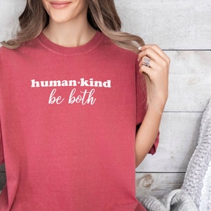May include: A red t-shirt with the text "human.kind be both" in white lettering.