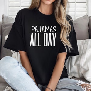 a woman sitting on a couch wearing a t - shirt that says pajamas