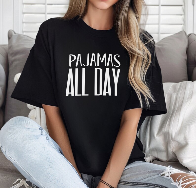 a woman sitting on a couch wearing a t - shirt that says pajamas