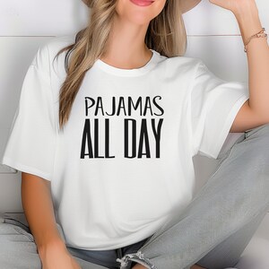 a woman wearing a white t - shirt that says pajamas all day