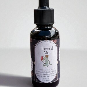 May include: A dark glass bottle with a black dropper and a label that reads "Uncord Me." The label also says "Flower Essence Blend" and "Sacred Lore Botanicals." The bottle contains 2 fl oz (60ml).