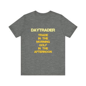 May include: A heather gray t-shirt with the text "DAYTRADER TRADE IN THE MORNING GOLF IN THE AFTERNOON" in yellow.