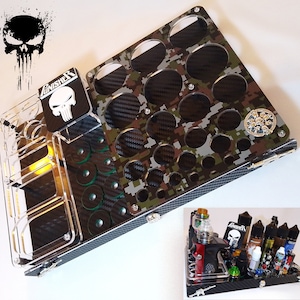 May include: A multi-compartment organizer with a camouflage pattern and carbon fiber accents. Features a clear acrylic section with the Punisher skull logo and a smaller, similar organizer in the bottom right corner. Includes various circular openings and storage slots.