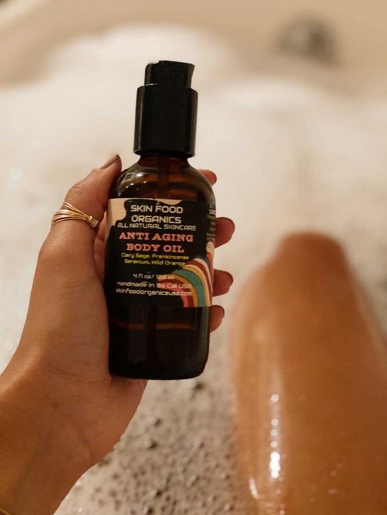 K&ouml;nnte beinhalten: Eine braune Glasflasche mit schwarzer Pumpenaufsatz und einem Regenbogen-Etikett. Das Etikett lautet "Skin Food Organics All Natural Skincare Anti Aging Body Oil Clary Sage, Frankincense, Geranium, Wild Orange 4 fl oz/120 ml Handmade in So Cal USA skinfoodorganicsusa.com".