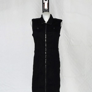May include: A black sleeveless dress with a zipper down the front, displayed on a black metal stand with a triangular base.