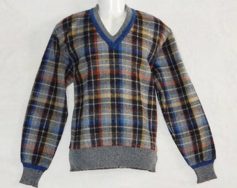 Puede incluir: Un suéter gris, azul y naranja a cuadros con cuello en V y ribete azul. El suéter tiene mangas largas y un dobladillo de canalé.