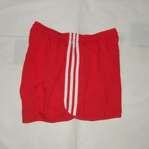 May include: Red athletic shorts with white stripes down the sides.