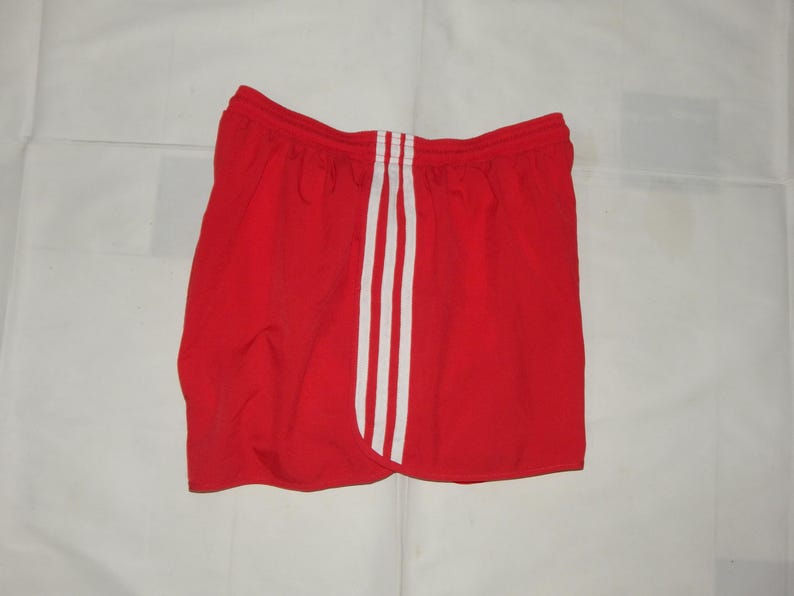 May include: Red athletic shorts with white stripes down the sides.
