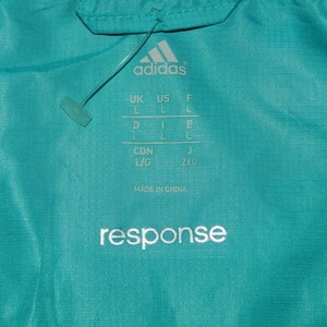 May include: A turquoise blue Adidas jacket with a white "response" logo and size chart. The size chart includes UK, US, F, D, CDN, and J sizes.
