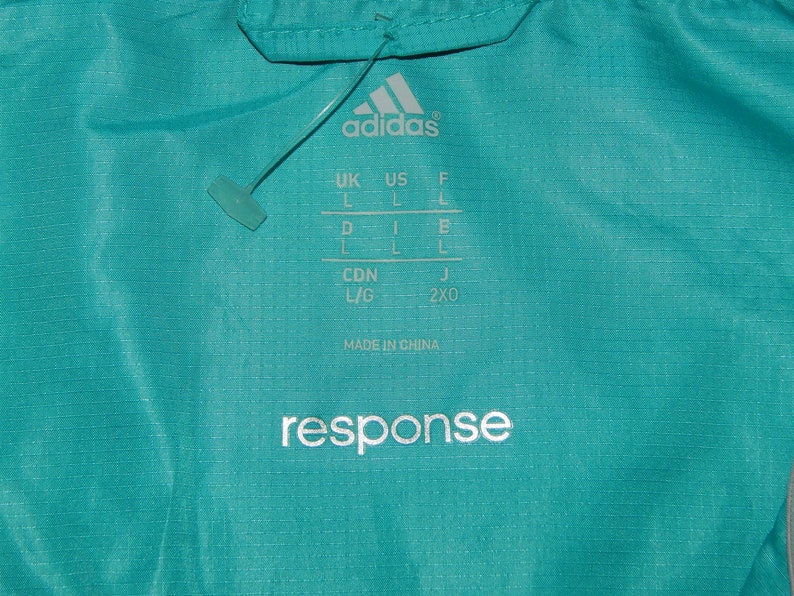 May include: A turquoise blue Adidas jacket with a white "response" logo and size chart. The size chart includes UK, US, F, D, CDN, and J sizes.
