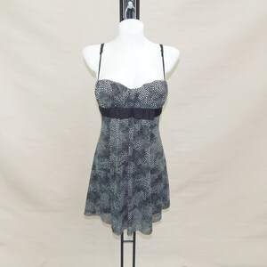 May include: A black and white polka dot dress with a black satin ribbon at the waist. The dress has a sweetheart neckline and thin straps.