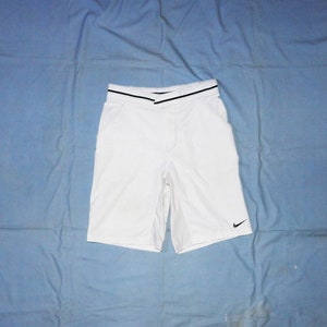 Può includere: Pantaloncini sportivi bianchi con cintura nera e logo Nike nero a forma di swoosh sulla gamba destra.