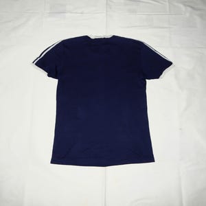 May include: A navy blue t-shirt with white trim around the neckline and sleeves.