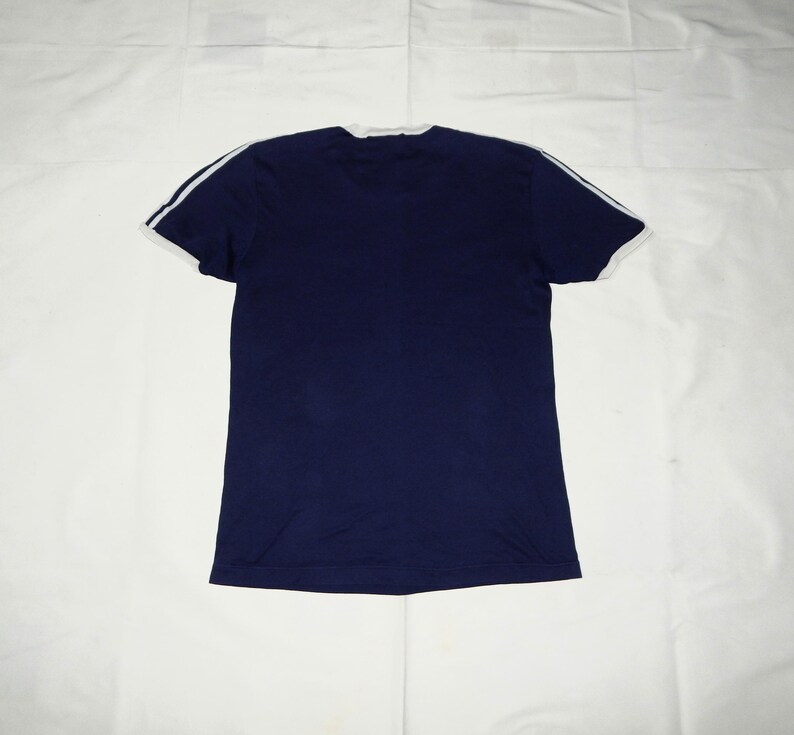 May include: A navy blue t-shirt with white trim around the neckline and sleeves.