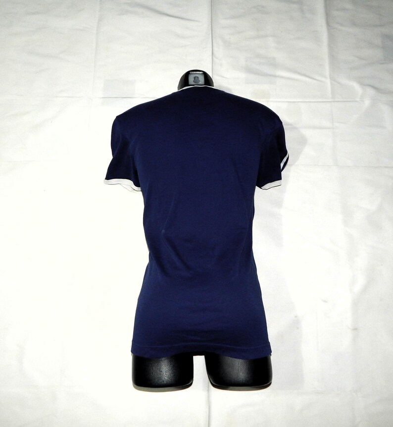 May include: A navy blue t-shirt with white trim around the neckline and sleeves.