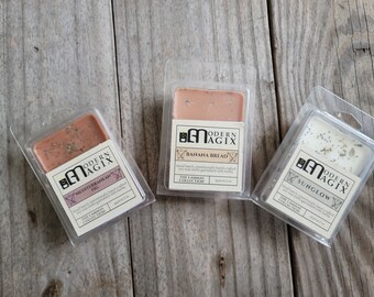 May include: Three wax melts in clear plastic packaging. The wax melts are labeled "Mediterranean Fig", "Banana Bread", and "Sunglow". Each wax melt is approximately 2 oz.