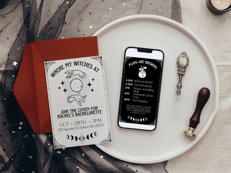 May include: A white card with black text and illustrations of hands holding a moon. The text reads "Where my witches at" and "Join the coven for Rachel's bachelorette Oct 28th 7pm 123 Spooky St Salem, MA 01070". A smartphone with a black screen displaying a schedule of events for a hen party. The text on the screen reads "Plans are brewing" and lists the times and activities for the day. The phone is on a white plate with a silver spoon and a wooden stamp.