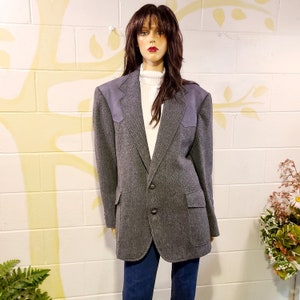 May include: A gray tweed blazer with suede elbow patches. The blazer has a single button closure and two front pockets.