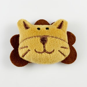 May include: A plush lion head toy with brown ears and a brown mane. The lion has a stitched-on face with brown eyes, a nose, and whiskers.