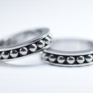 Puede incluir: Dos anillos de plata con una fila de peque&ntilde;as cuentas de plata alrededor de la banda.