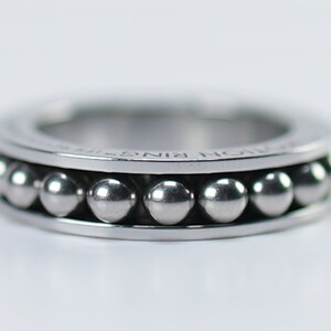 Puede incluir: Un anillo de plata con una fila de peque&ntilde;as cuentas de plata alrededor de la banda. El anillo est&aacute; inscrito con las palabras "NORM RING".