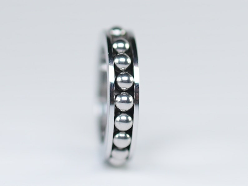 Puede incluir: Un anillo de metal plateado con una fila de peque&ntilde;as cuentas redondas alrededor del borde.