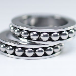 Puede incluir: Dos anillos de plata con una fila de peque&ntilde;as bolas de plata alrededor del borde.