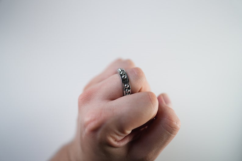 Puede incluir: Un anillo de plata con una fila de peque&ntilde;as cuentas redondas alrededor de la banda.