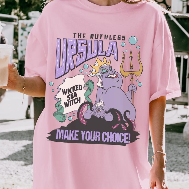 A person wearing a pink t-shirt with a graphic design featuring a character from the Disney animated film "The Little Mermaid".