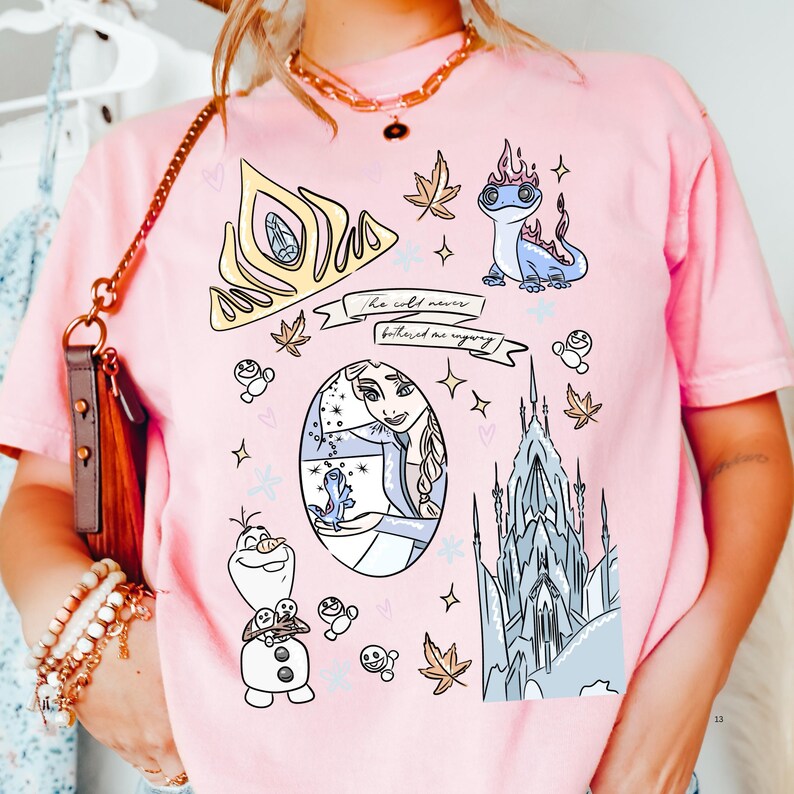 A pink t-shirt with various cartoon-style illustrations, including characters from the Disney movie Frozen, such as Olaf, Elsa, and the castle.