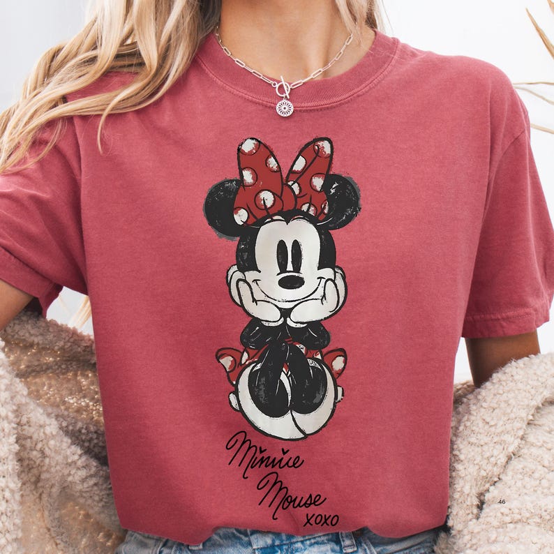 A person wearing a red t-shirt with a Minnie Mouse graphic printed on it.