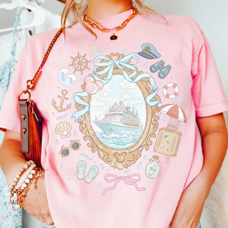 A person wearing a pink t-shirt with a graphic design depicting a cruise ship, surrounded by various nautical and travel-related icons.