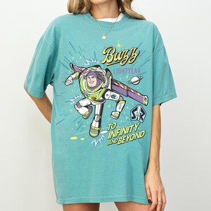 A person wearing a light blue t-shirt with a colorful graphic of Buzz Lightyear from the Toy Story franchise.