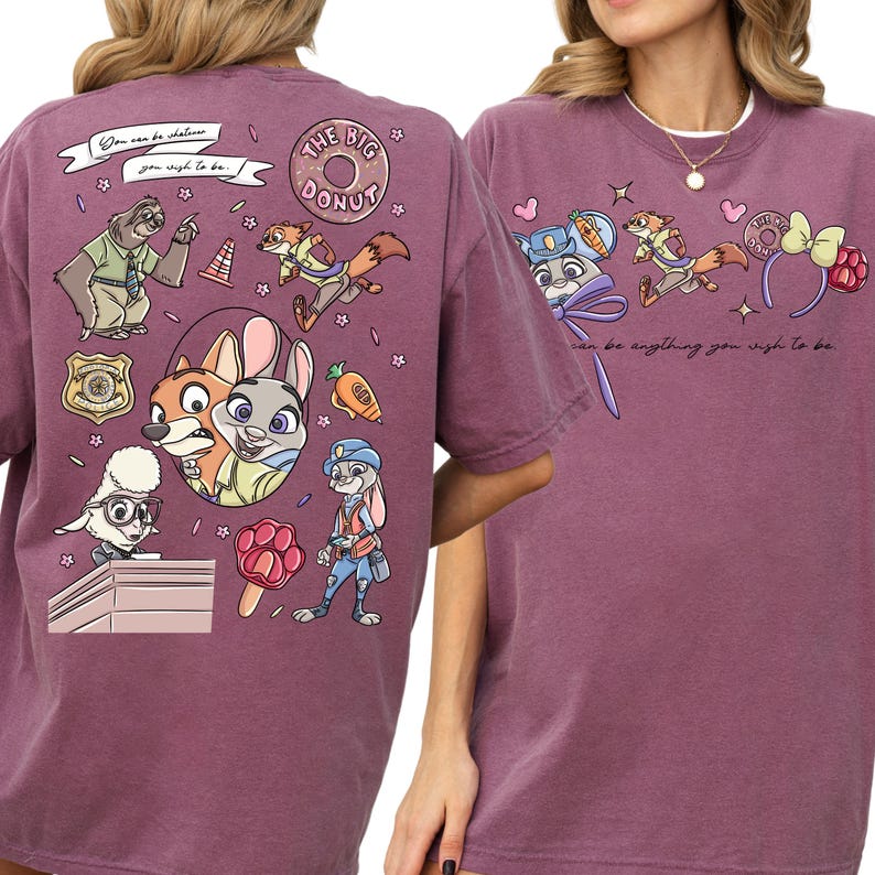 a purple t-shirt with a vibrant graphic design of cartoon characters, including a bear, a rabbit, and other animals, along with various objects like a carrot, a flower, and a sign.