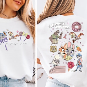 The image is a collage of two photos featuring a white t-shirt with a cartoon character design. The design includes various cartoon animals, such as a dog, cat, and rabbit, along with other colorful elements like flowers, a donut, and a sign. The text on the t-shirt reads "You can be anything you wish to be" and "The big donut".