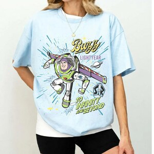 A person wearing a light blue t-shirt with a colorful graphic of Buzz Lightyear from the Toy Story franchise.