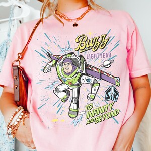 A person wearing a pink t-shirt with a graphic of Buzz Lightyear from the Toy Story franchise, along with the text "Lightyear to Infinity and Beyond".