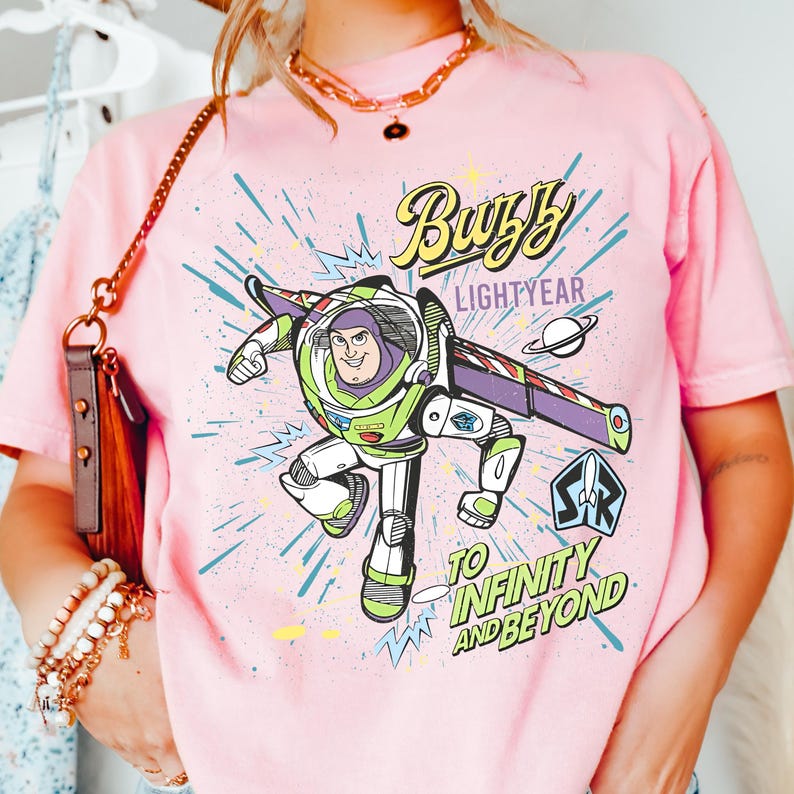 A person wearing a pink t-shirt with a graphic of Buzz Lightyear from the Toy Story franchise, along with the text "Lightyear to Infinity and Beyond".