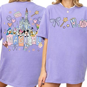 a purple t-shirt with a Disney-themed design, including Mickey Mouse, Minnie Mouse, Donald Duck, and other Disney characters. The t-shirt also has the word "MAGICAL" written on it.