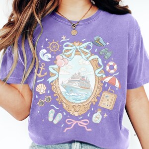 A person wearing a purple t-shirt with a graphic design depicting a cruise ship, nautical elements, and various icons.