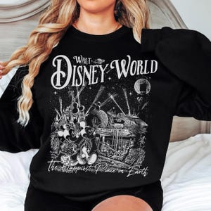 A woman wearing a black sweatshirt with a graphic design depicting Disney World.