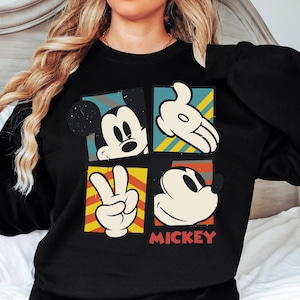 A woman wearing a black shirt with a graphic design featuring Mickey Mouse and the word "MICKEY" printed on it.