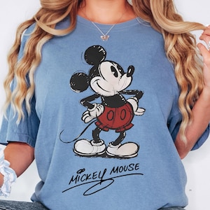 A woman wearing a blue t-shirt with a Mickey Mouse graphic printed on it.