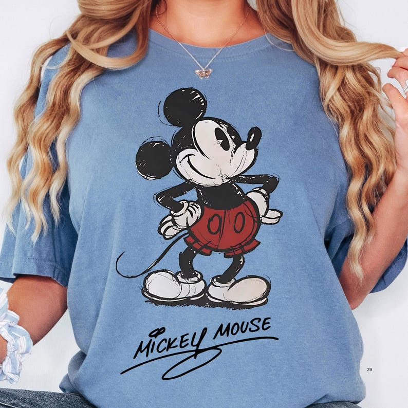 A woman wearing a blue t-shirt with a Mickey Mouse graphic printed on it.