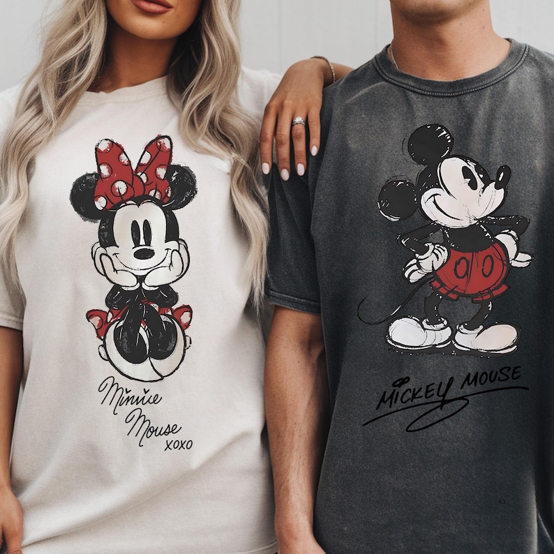 A woman and a man standing next to each other, both wearing t-shirts with Mickey Mouse designs.