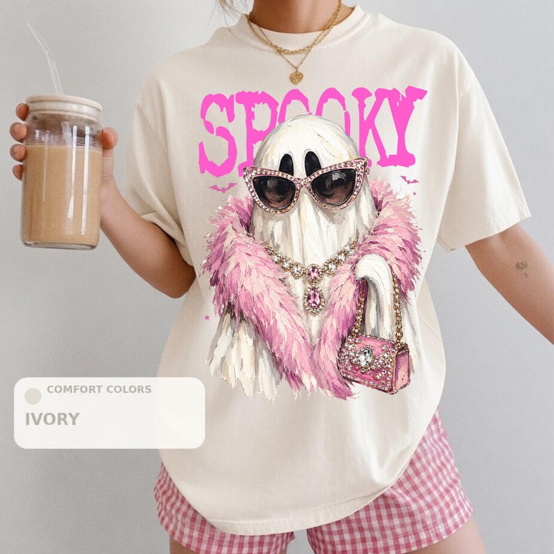 A person wearing a white t-shirt with a graphic of a ghost wearing sunglasses, a pink feathered scarf, and holding a drink.