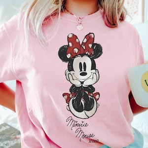 A person wearing a pink t-shirt with a Minnie Mouse graphic printed on it.
