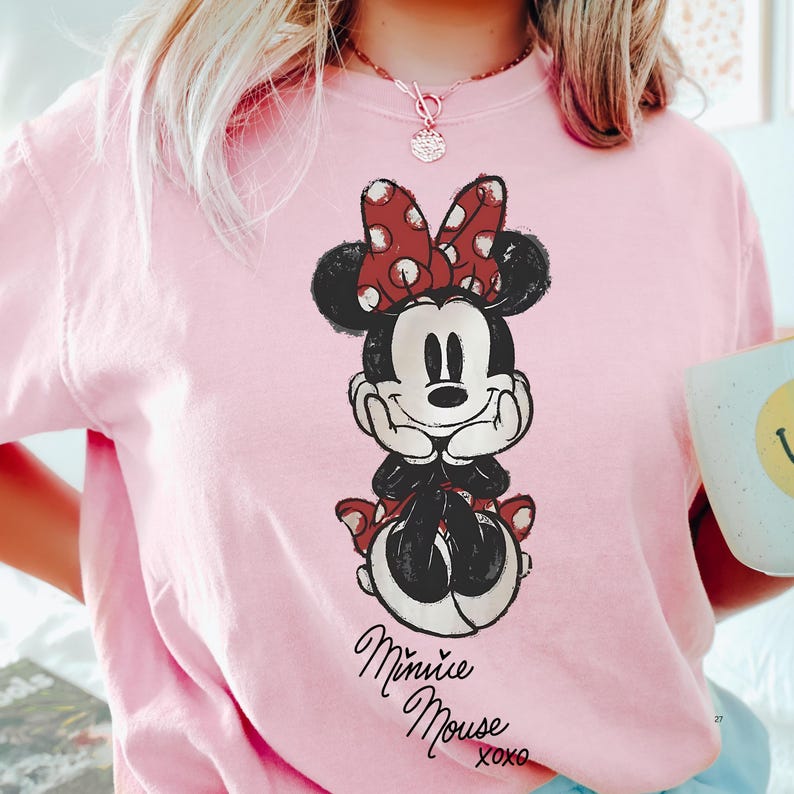 A person wearing a pink t-shirt with a Minnie Mouse graphic printed on it.
