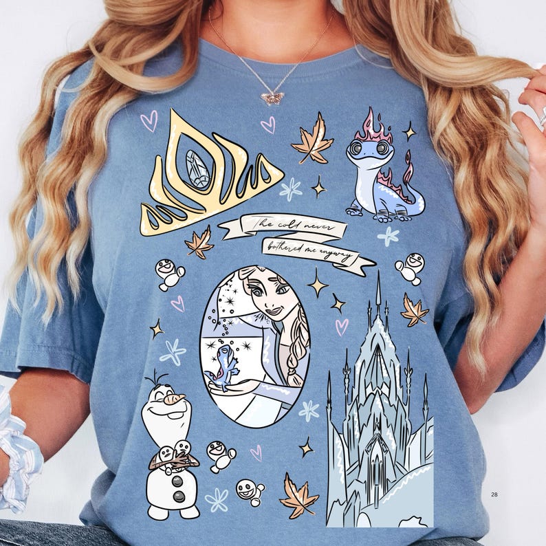 A woman wearing a blue t-shirt with various cartoon-style illustrations and characters, including a princess, a dragon, and a castle.